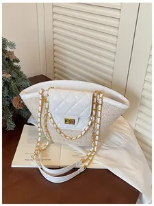 Détail d'un sac panier en paille tressée avec rabat matelassé blanc et chaîne dorée