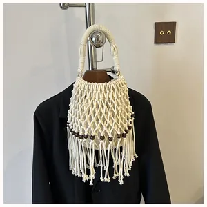 Close-up of white macrame woven bucket bag with wooden beads and long tassels