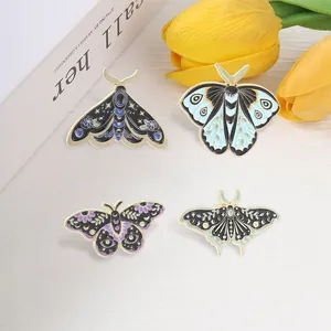 Macro detail of four mystical moth and butterfly enamel pins with celestial patterns.
