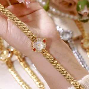 Primer plano de un elegante reloj de pulsera vintage dorado con detalles en rojo rubí