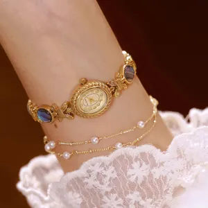 Primer plano de un reloj de pulsera dorado con incrustaciones de abulón y perlas