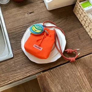 Detailed view of an orange mesh drawstring bucket bag with a banana charm