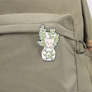 Enamel cat pin featuring a kitten in a jar with green leaves on a canvas backpack