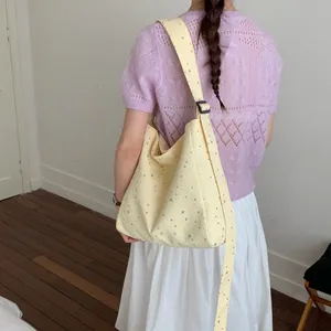 Detailed view of large capacity yellow canvas tote bag with star prints on model.
