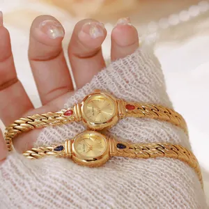 Primer plano de reloj dorado con piedras de circón rojas y azules