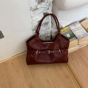Deep red faux leather tote bag with stylish belt buckle detail in lifestyle setting