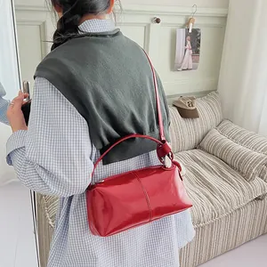 Stylish woman wearing a trendy red glossy retro pillow handbag in an indoor setting