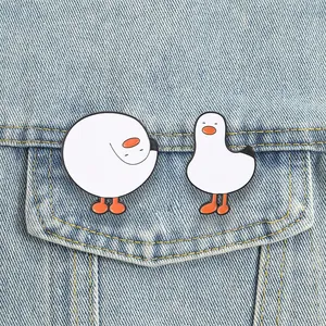 Gedetailleerde weergave van twee schattige witte gans emaille pinnen op een spijkerjasje.