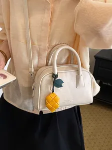 Elegant cream pillow handbag with top handles and a decorative yellow woven lemon charm