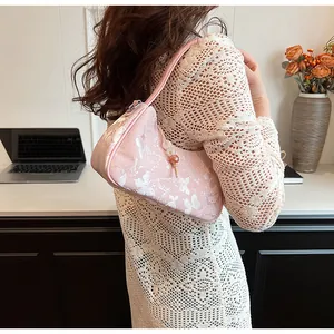 Detail shot of pink jacquard underarm bag with butterfly pattern and beaded charm decoration