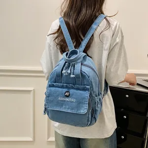 Rückansicht einer Frau mit einem hellblauen Jeansrucksack in einem modernen hellen Zimmer