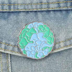 Makro-Detail der künstlerischen blau-grünen Emaille-Anstecknadel auf einer Jeansjacke