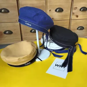 Detail of beret hats in various colors with Forever embroidery and long silk ribbons.
