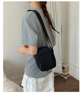 Nahaufnahme einer stylischen schwarzen Mini-Umhängetasche, getragen von einem Modell