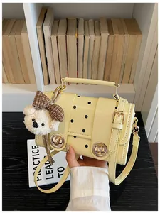 Close-up of a cream retro polka dot crossbody bag featuring a cute plush bear charm