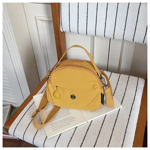 Detalle de bolso bandolera de nailon amarillo con varios compartimentos en una silla