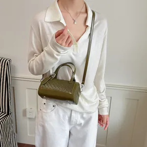 Vista dettagliata di una borsa a cilindro intrecciata verde oliva indossata da una modella