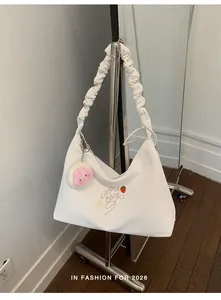 Detalle de un bolso de hombro blanco con correa plisada y lindo bordado de fresas