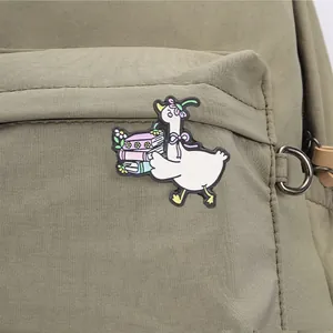 Detailopname van een speelse witte gans emaille speld met boeken op een groene tas.