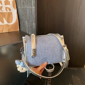 Close-up of a stylish blue denim pillow bag with silver hardware and a cute bear charm