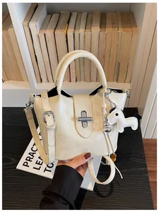 Vue détaillée d'un élégant sac seau blanc crème doté d'un joli charme de cheval blanc