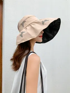 Side profile of a woman wearing a beige butterfly print sun hat with black glue lining.