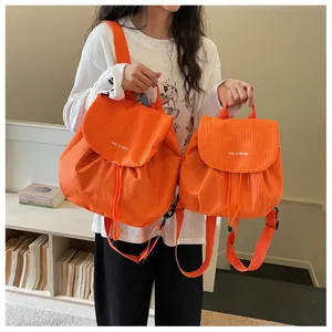 Detail showing the contrast between large and small sizes of the orange plaid backpack