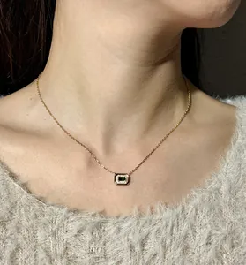 Detailed shot of emerald cut green stone necklace with gold finish on model neck