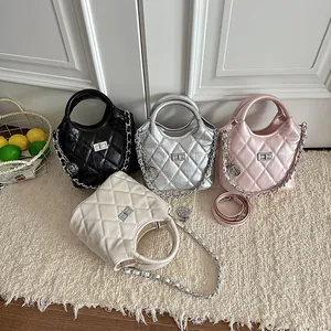 Detail shot of four quilted bucket bags in black, silver, pink, and cream with chain straps.