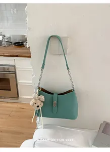 Vista dettagliata di una borsa sottobraccio in pelle martellata verde menta con orsetto