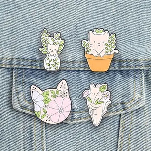 Detailed view of four cute cartoon cat enamel pins featuring green plants and floral designs.