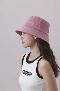 Vista lateral de un gorro de pescador rosa de verano con bordado en una linda modelo