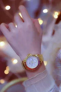 Luxury gold-tone women's watch with rainbow crystal bezel and shimmering dial