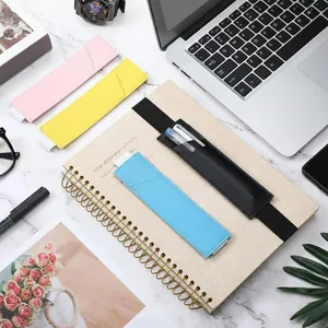 Étuis à stylos élastiques en similicuir colorés sur un carnet à côté d'un ordinateur.
