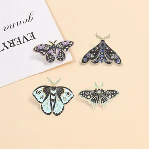 Close-up of vintage mystical moth and butterfly enamel pins with celestial floral patterns.