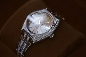 Primer plano de un lujoso reloj cuadrado plateado para mujer con bisel de cristales brillantes