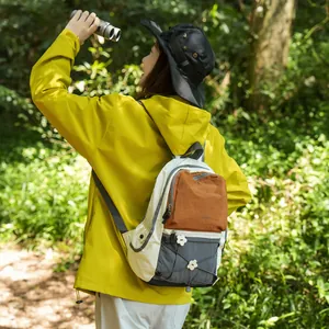 Frau trägt einen farbenfrohen Outdoor-Rucksack beim Wandern im üppigen grünen Wald.