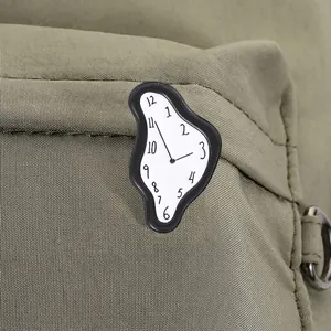 Primer plano de un pin de esmalte de reloj derretido surrealista en una mochila de tela verde