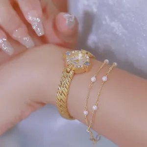 Primer plano detallado de un reloj vintage dorado con pulsera de perlas a juego.
