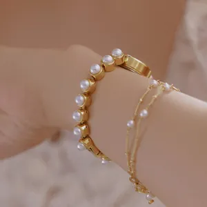 Nahaufnahme einer luxuriösen goldfarbenen Damenuhr mit elegantem Armband aus Kunstperlen