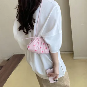 Stylish pink polka-dot crossbody pouch bag shown on a model in a casual setting