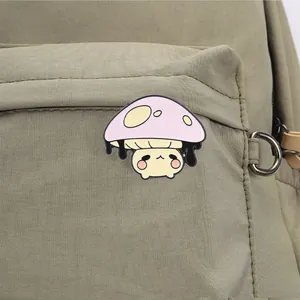 Cute anthropomorphic mushroom enamel pin displayed on an olive green backpack pocket.