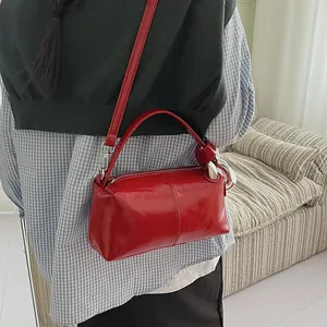 Close-up of a stylish red retro pillow bag worn as a crossbody handbag in a lifestyle setting
