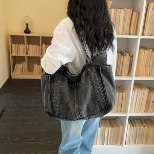 Vue détaillée d'un grand sac cabas en denim noir délavé porté par un mannequin stylé
