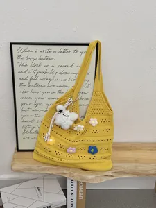 Gelbe handgefertigte Häkeltasche mit bunten Blumenapplikationen und Plüschanhänger