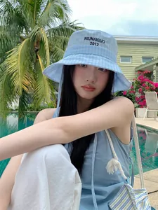 Vista dettagliata di un cappello da pescatore a scacchi blu con ricamo su una modella