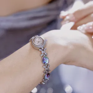 Vista detallada de un elegante reloj de pulsera plateado con incrustaciones de concha abulón