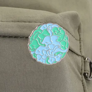 Detailaufnahme der blau-grünen Emaille-Anstecknadel mit abstrakten Figuren auf grüner Tasche