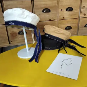 Detail view of stylish beret hats in white, khaki, and black with long bow ribbons.