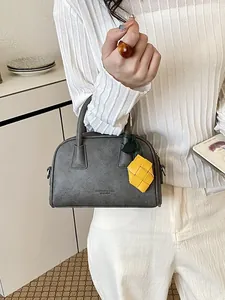 Sophisticated grey pillow bag for women with decorative yellow woven charm